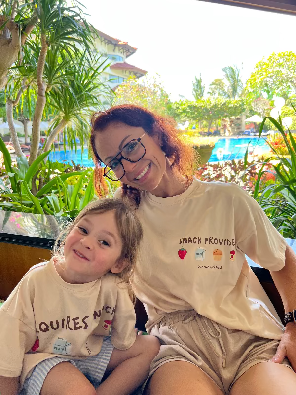 Mum and child sitting by the pool, on holiday, wearing matching shirts