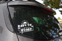 Car window with 'Baby on Board' sticker and raindrops