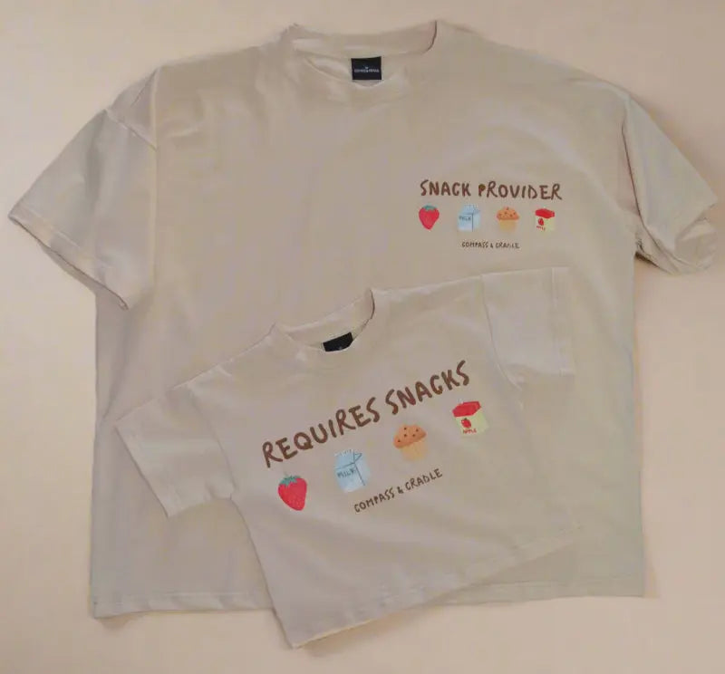 Two beige-colored t-shirts with snack-themed graphics and text on a beige background