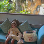 child sitting on couch wearing an oversized t-shirt next to an oversized tote bag