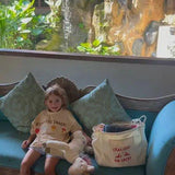child sitting on couch wearing an oversized t-shirt next to an oversized tote bag