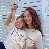 mum and daughter wearing matching t-shirts with graphic designs against a white lattice background