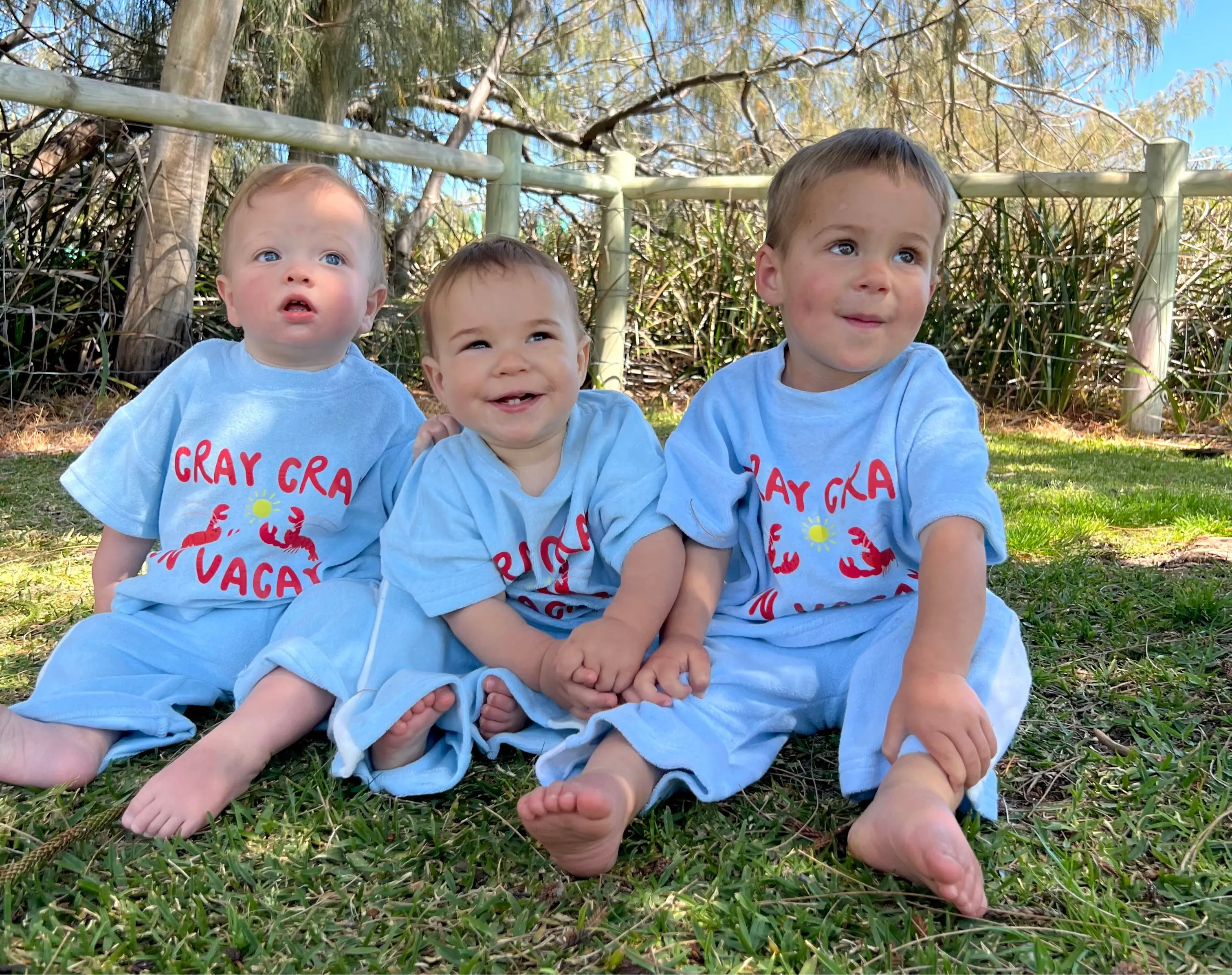 Children sitting together in matching shirts, matching pants in the park for summer