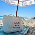 Beige beach tote bag with colourful logo on a beach holiday under an umbrella 