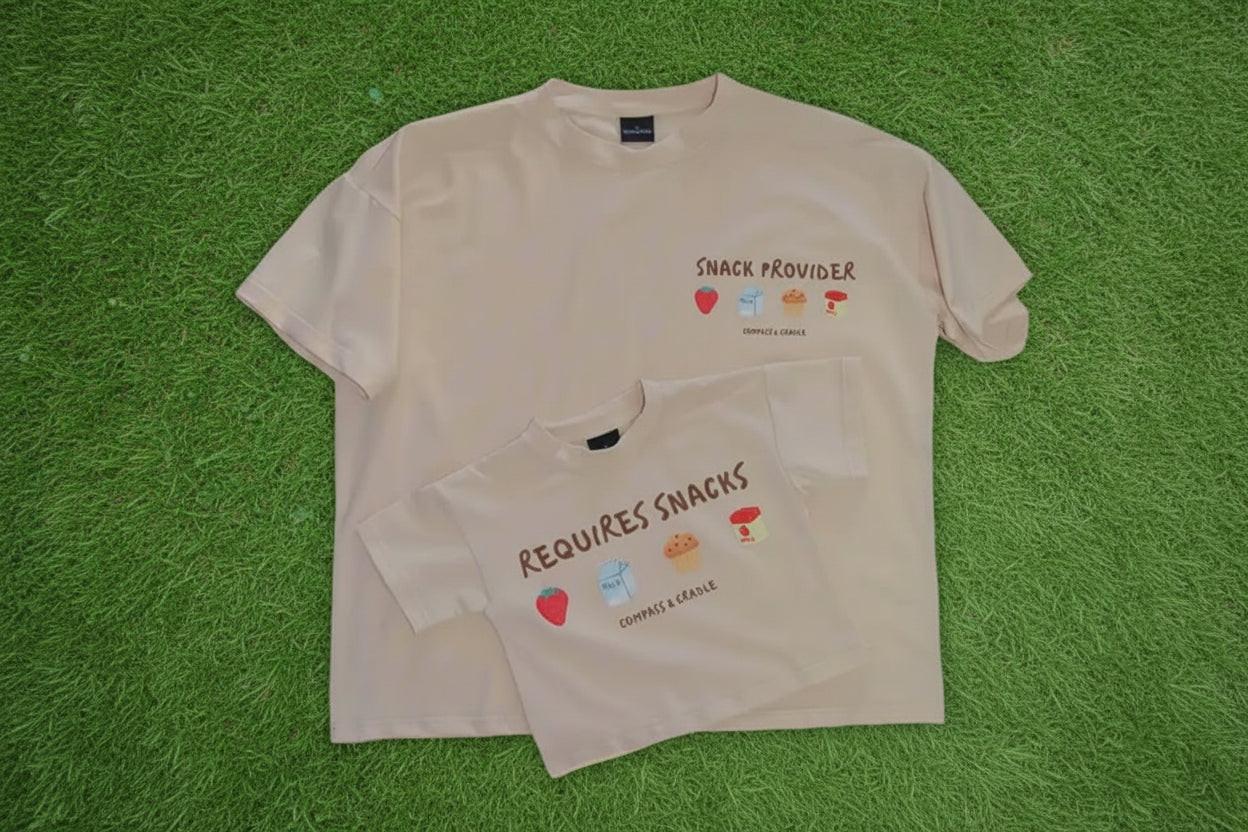 Two beige-colored t-shirts with snack-themed graphics and text on a beige background